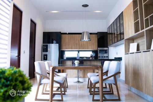 a kitchen with a wooden table and white chairs at S- Penthouse Executive Norte - Alegría Housing in Aguascalientes