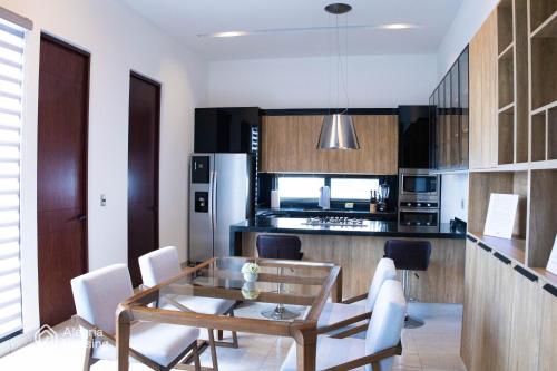 a kitchen with a glass table and white chairs at S- Penthouse Executive Norte - Alegría Housing in Aguascalientes