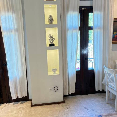 Una habitación con cortinas blancas y una puerta con ventana. en Casa De Mabel, en Santo Domingo