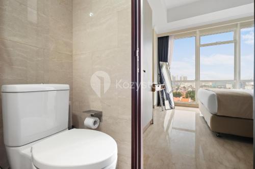 a bathroom with a toilet and a bed and a window at Alden by Kozystay - Menteng in Jakarta