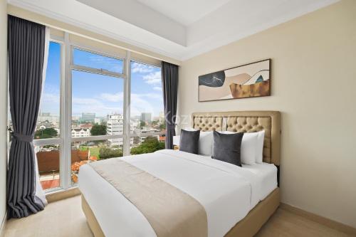 a bedroom with a large bed and a large window at Alden by Kozystay - Menteng in Jakarta