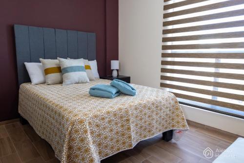 ein Schlafzimmer mit einem Bett mit zwei blauen Kissen darauf in der Unterkunft T - Apartamento Privado - Alegría Housing in Aguascalientes