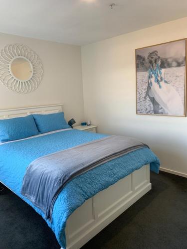 a bedroom with a blue bed with a picture on the wall at 7th Floor Apartment in Geelong