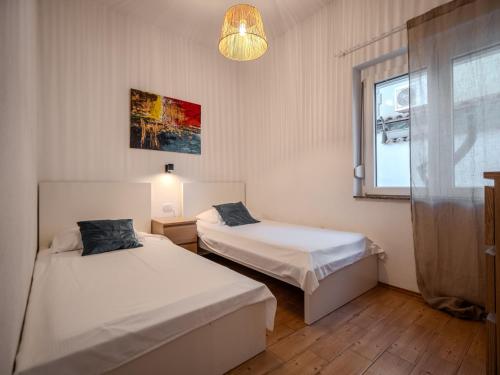 a bedroom with two beds and a window and a lamp at Sunset apartments Njivice in Njivice