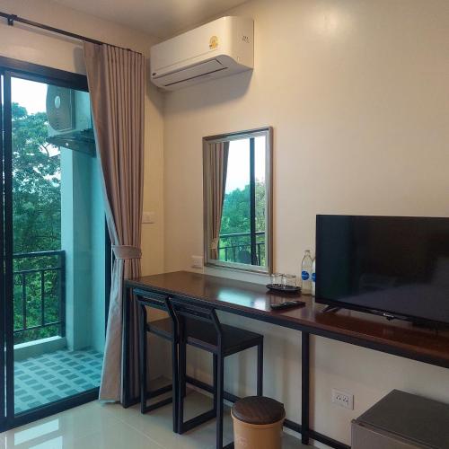a room with a desk with a television and a window at Top Place in Ban Pang Kae
