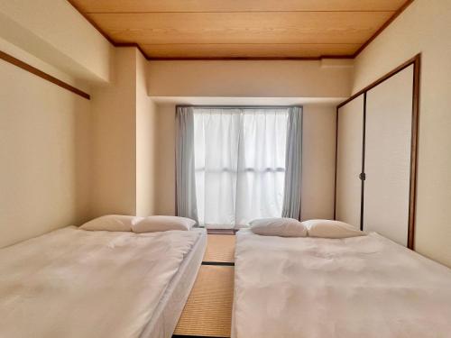 two beds in a room with a window at LoveAsakusa Stay 6 Iriya Station Ueno Station 2ー6人 エレベーター WIFI 浅草 新宿 渋谷 銀座 築地 浅草 原宿近い in Tokyo