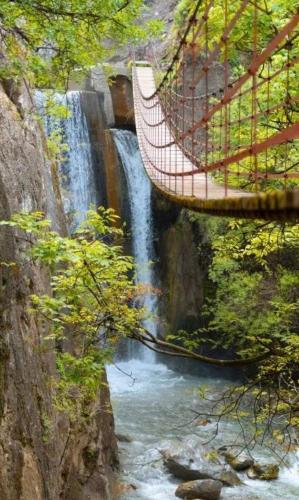 a suspension bridge over a river with a waterfall at Encarnita Apartamento - Monachil in Monachil