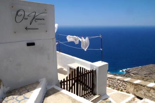 a white building with a fence and the ocean at Oxo Kamara Apartment in Karpathos Town