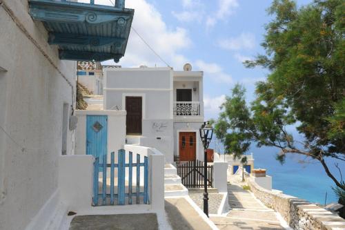 a white building with blue doors and stairs next to the ocean at Oxo Kamara Apartment in Karpathos Town
