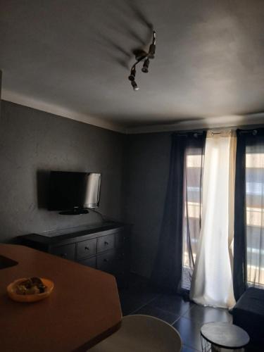 un salon avec une télévision et une table et une chambre avec dans l'établissement A 30m de la place Med, à Canet