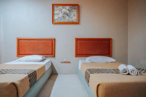 a room with two beds and a picture on the wall at Hotel Wisma Dago in Bandung