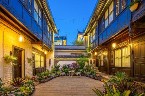 a courtyard of an old building with tables and flowers at Yueju Designer Homestay in Lijiang