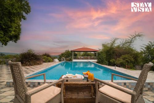 a swimming pool with a table and chairs next to it at StayVista at Bayleaf Villa with Pool, Lawn, Wi-Fi in Nashik