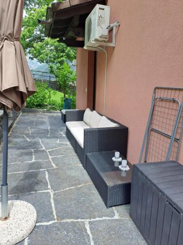 a patio with a couch and an umbrella at Casa Di Vacanza Cevio in Cevio