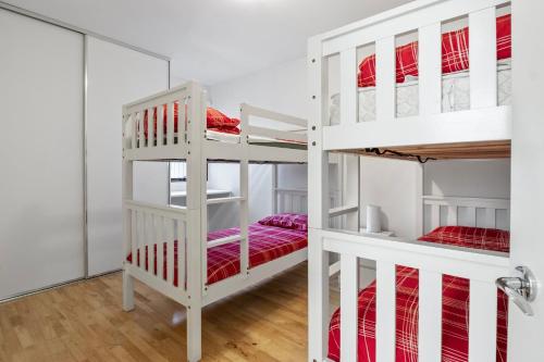 Ce lit se trouve dans un dortoir doté de 2 lits superposés blancs. dans l'établissement South Shores Villa 50, à Normanville