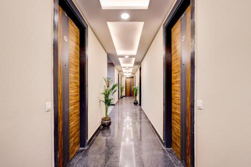 a hallway with white walls and wooden doors and a plant at The Byke Business Hotel - Sector 29 in Gurgaon