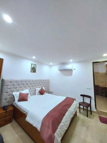 a bedroom with a large bed and a chair at Vinayak Stay Sector 43 in Gurgaon