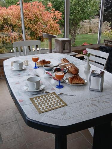 une table avec des croissants, des tasses et des boissons dessus dans l'établissement Chambre sérénité, à Moult