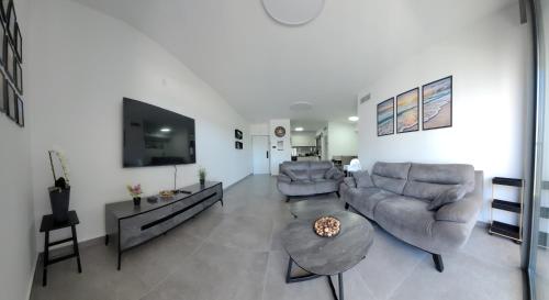 a living room with two couches and a flat screen tv at חלון לים - דירת נופש באכזיב in Nahariyya