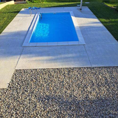 a swimming pool in a yard with a sidewalk and grass at Apartments Bukor with seasonal pool in Lukovica pri Domžalah