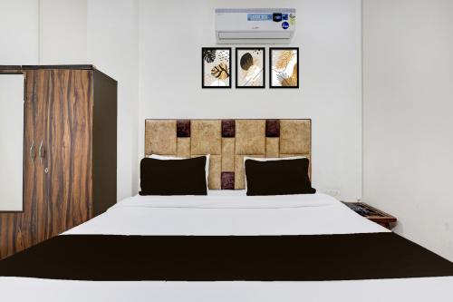 a bedroom with a large white bed with black pillows at Hotel O Rajeev Nagar Faridabad in Faridabad
