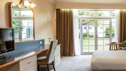a hotel room with a desk with a bed and a mirror at Wairakei Resort Taupo in Taupo
