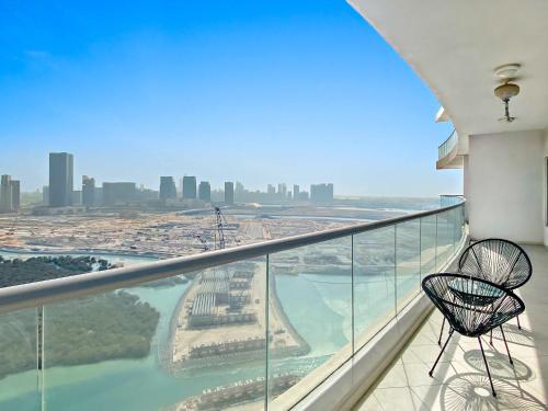 d'un balcon avec deux chaises et une vue sur la ville. dans l'établissement Silkhaus Modern 2 BDR | Sea View | Oceanscape, à Abu Dhabi