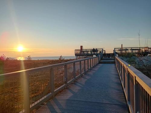une promenade en bois menant à la plage au coucher du soleil dans l'établissement Darłówko 300m plaża Kładkowe Studio 1, à Darłowo