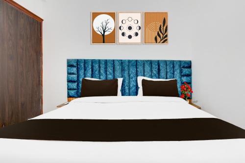 a bedroom with a white bed with a blue headboard at Super Townhouse Sector 1 Manesar in Manesar