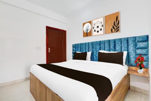 a bedroom with a large bed with a blue headboard at Super Townhouse Sector 1 Manesar in Manesar