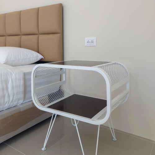 a white glass table next to a bed at Top Place in Ban Pang Kae