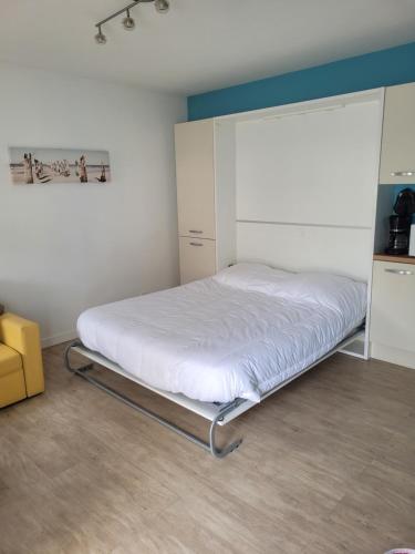 un lit dans une chambre blanche avec un cadre de lit dans l'établissement Appartement avec piscine et accès direct à la mer, à Châtelaillon-Plage
