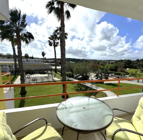 balcone con tavolo in vetro, sedie e palme di Casa Zen Apartamentos Santa Teresinha Montes de Alvor ad Alvor
