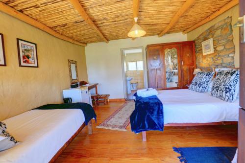 a bedroom with two beds and a wooden ceiling at Over The Mountain Guest Farm in George
