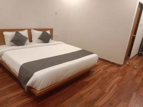 a bedroom with a bed with white sheets and gray pillows at Hotel Nikunj, Kilerama in Ashta