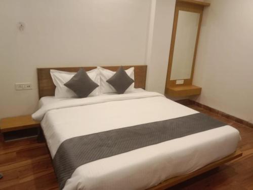 a bedroom with a large white bed with gray pillows at Hotel Nikunj, Kilerama in Ashta