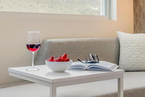 a glass of wine and a bowl of strawberries on a table at Cambria Hotel Burbank Airport in Burbank