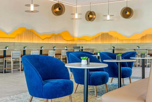 a dining room with blue chairs and tables at Cambria Hotel Burbank Airport in Burbank