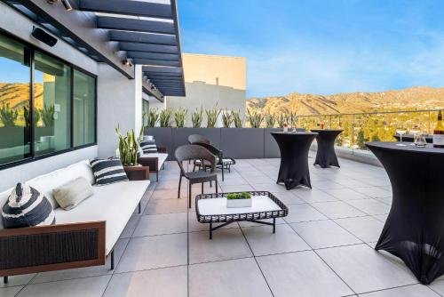a patio with a white couch and chairs and tables at Cambria Hotel Burbank Airport in Burbank