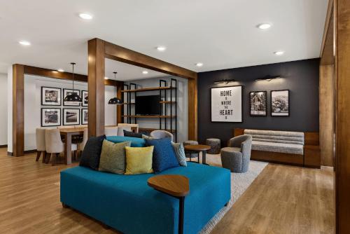 a living room with a blue couch and a dining room at Everhome Suites Ontario in Ontario