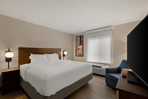 a bedroom with a large white bed and a television at Everhome Suites Ontario in Ontario