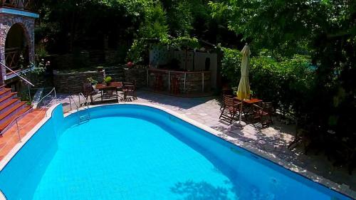 a large blue swimming pool with a table and chairs at Kazaviti Luxury Suites in Mikrós Prínos