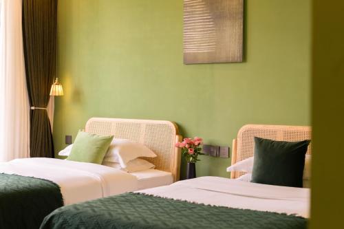 two beds in a room with green walls and flowers at Viewing Mount with Jun in Lijiang