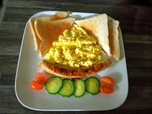 a plate of breakfast food with a hot dog and eggs at Camdene Guesthouse in Cape Town