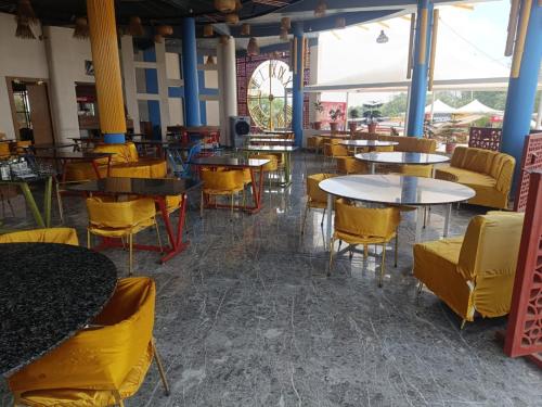 an empty restaurant with tables and yellow chairs at Hotel Nikunj, Kilerama in Ashta