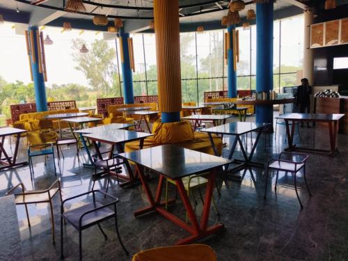 a group of tables and chairs in a room with windows at Hotel Nikunj, Kilerama in Ashta