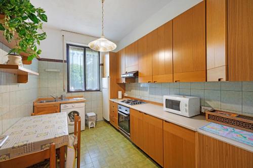 Una cocina con gabinetes de madera y un microondas blanco. en Appartamento immerso nel verde, en Lanzo d'Intelvi