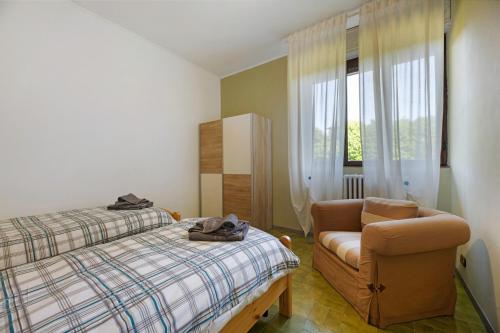 a bedroom with a bed and a chair and a window at Appartamento immerso nel verde in Lanzo dʼIntelvi