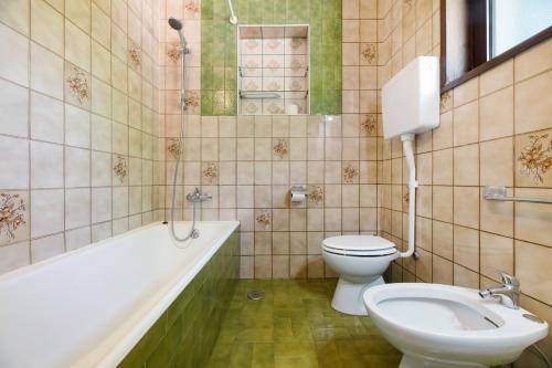 a bathroom with a toilet and a tub and a sink at Appartamento immerso nel verde in Lanzo dʼIntelvi
