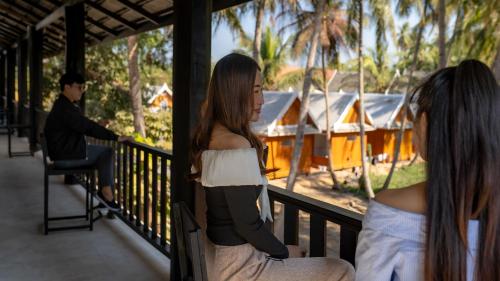 a couple of women sitting on a balcony with a man at Luang Prabang Vang Luang Hotel in Luang Prabang
